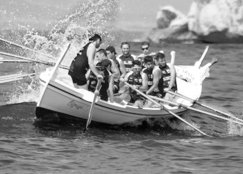 Group of men on a boat navigating a big wave