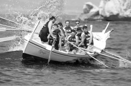 Group of men on a boat navigating a big wave